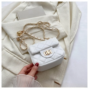 Detail of white quilted crossbody bag with golden twist lock and chain strap on a blazer