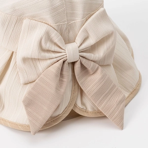 Elegant beige sun hat for women featuring a large bow and textured sun protection fabric