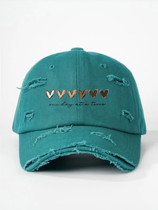 Detail view of distressed cyan baseball cap with heart prints and one day at a time text