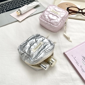 Close-up of heart-quilted PU leather sanitary pad storage bags in silver and pink colors