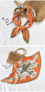 Detail of pleated silk scarf featuring orange and green floral print with satin texture