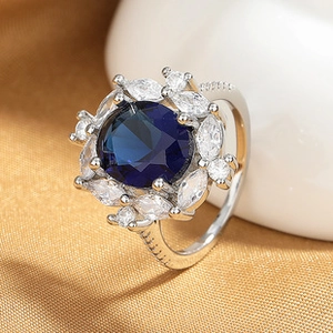 Macro detail of silver ring featuring a blue round gemstone with marquise-cut accents