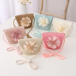 Close-up of six colorful children straw bags with 3D floral accents and woven straps