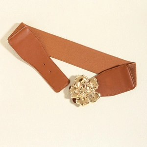 Détail d'une large ceinture élastique marron avec boucle fleur en métal doré chic
