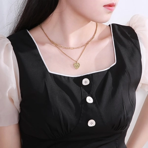 Close-up of double-layer gold heart necklace with rectangular link chain on a model