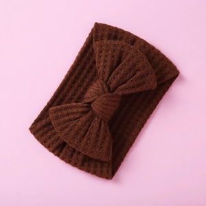 Close-up of deep brown waffle knit baby headband with a decorative soft bow detail