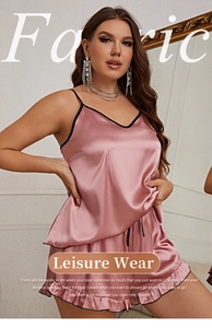 Detail of pink satin sleepwear set showing V-neck camisole and ruffled shorts with black trim