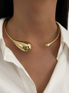 Detail of high-polish gold teardrop open collar necklace shown on a model
