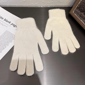 Nahaufnahme cremefarbener Strickhandschuhe mit weicher Textur und gerippten Bündchen auf Holz