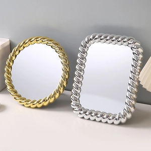 European vintage vanity mirror with gold and silver ornate frames on a grey desktop
