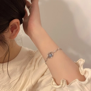 Close-up of a silver star charm bracelet with a central blue gemstone on a woman's wrist
