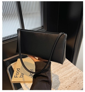 Close-up of black leather underarm bag with smooth texture against striped glass