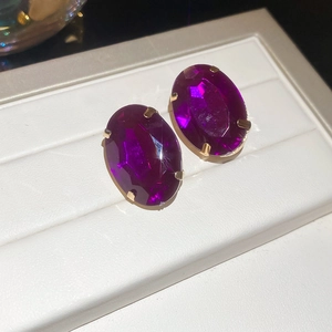 Detail shot of vintage oval purple gemstone earrings with gold four-prong setting
