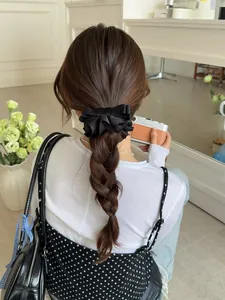 Élégant nœud papillon en satin noir multicouche sur une coiffure en tresse haute