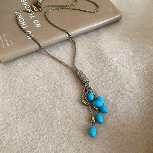 Close-up of bohemian bronze necklace featuring turquoise bead tassels on a vintage book