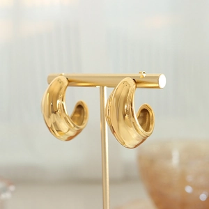 Minimalist thick gold C-shaped hoop earrings displayed on a professional T-stand holder