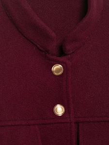 Détail de la veste en laine bordeaux avec deux boutons en métal doré texturé sur tissu