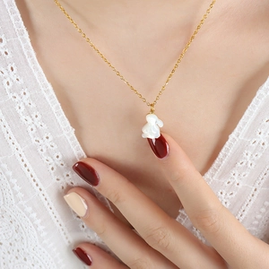 Collier doré minimaliste avec pendentif lapin blanc porté par modèle sur dentelle