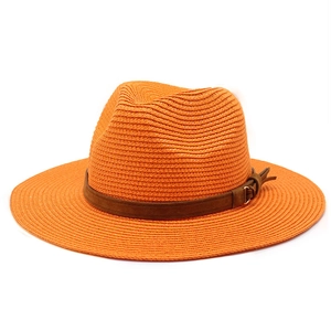 Close-up of vibrant orange woven straw fedora hat with brown leather band and gold buckle