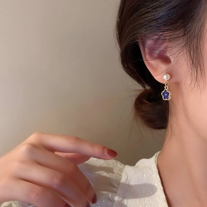 Elegant gold flower drop earrings with Klein blue enamel and pearl on model