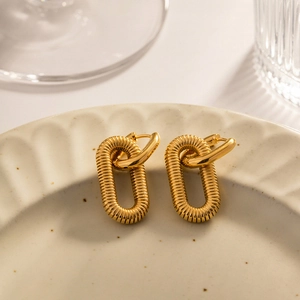 Detail of gold-plated chain link earrings featuring a spiral texture pendant in a tray