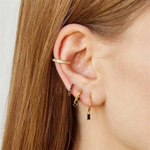 Close-up of gold stacking ear set featuring floral crystal ear cuff and black stone hoops