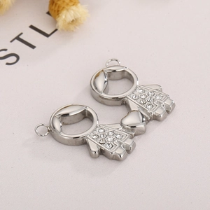 Détail de pendentifs de couple en acier titane argenté avec strass et lien en forme de cœur