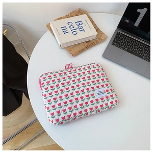 Detailed macro of white quilted laptop sleeve featuring red tulip pattern and pink zipper
