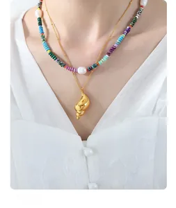 Detail of layered gold necklace featuring natural pearls, colorful beads and a conch charm