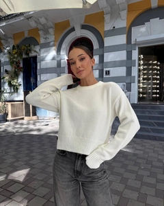 Close-up of ribbed cuffs and hem details on this white crewneck knit sweater