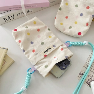 Close-up of colorful polka dot canvas phone bag with mint green braided rope strap