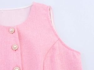 Nahaufnahme der rosa Tweed-Weste mit eleganten Perlenknöpfen und gewebten Stoffdetails