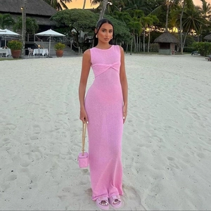 Détail de la robe tricotée rose sans manches avec un nœud élégant devant sur fond de plage