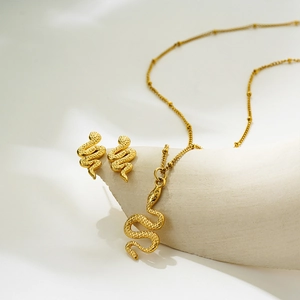 Golden snake-themed jewelry set with scale texture on white stone decorative blocks