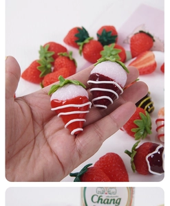 Detailed view of artificial strawberry pendants with realistic texture and chocolate icing