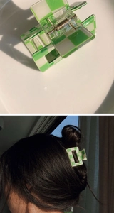 Detail of green and white checkered hair claw clip shown on a plate and in hair