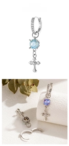 Detail of silver iris cross earrings with blue crystal pendant on white stone base