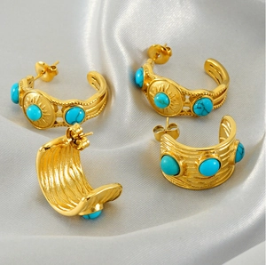 Détail de boucles d'oreilles dorées vintage avec turquoise sur tissu de soie gris