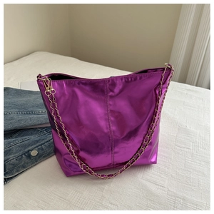 Detail of metallic purple PU bucket bag with gold chain strap on a white bed