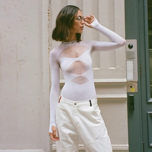 Détail du body blanc à découpes en maille avec finition strass et manches longues