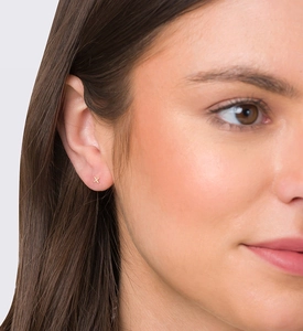Close-up of small gold cross stud earring in S925 silver on a female model