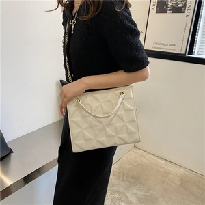 Detail of 3D geometric pyramid texture and gold chain strap on stylish white crossbody bag