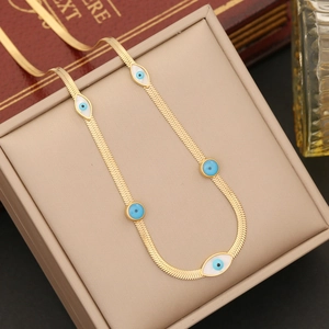 Golden snake chain necklace featuring blue and white eye-shaped pendants on a jewelry box