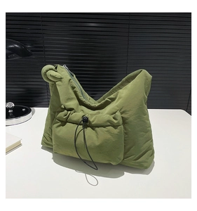 Close-up of grass green quilted nylon crossbody bag with drawstring pocket and knotted strap