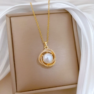 Elegant gold necklace with pearl and crystal nest pendant on silk jewelry box display