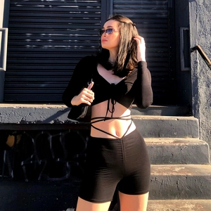 Detail view of black long sleeve cross-tie crop top and high waist slim fitness shorts