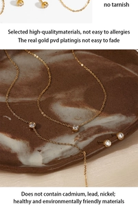 Detail of PVD gold plated necklace and earrings set with zircons on marble tray
