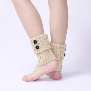 Detail of beige cable knit leg warmers with black buttons for winter boots wear