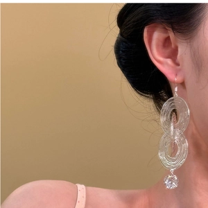 Detail of silver layered oval earrings with sparkling zircon on a female model