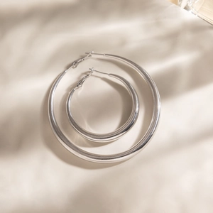 Minimalist polished stainless steel hoop earrings in two sizes with soft shadow lighting